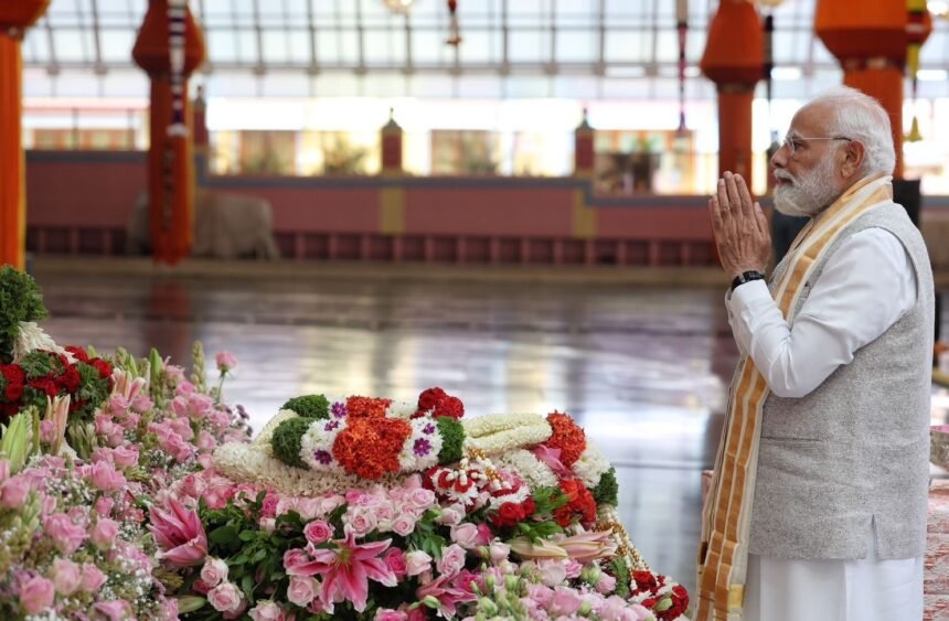 प्रधानमंत्री नरेंद्र मोदी सत्य साई बाबा मंदिर में पुष्पांजलि अर्पित करते हुए