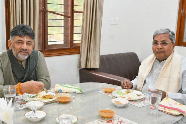 सिद्धारमैया और डीके शिवकुमार एक टेबल पर बैठकर बातचीत करते हुए ब्रेकफास्ट मीटिंग में शामिल हैं।