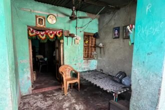 रैपिडो बाइक पर एक पुलिस अधिकारी मनी लॉन्ड्रिंग और ऑनलाइन सट्टेबाजी की जाँच के प्रतीक के रूप में बैंक दस्तावेजों की जाँच कर रहा है।