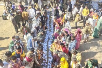मध्य प्रदेश के राजगढ़ जिले में एक सहकारी विपणन समिति कार्यालय के दरवाजे पर किसान अपने आधार कार्ड और जमीन के दस्तावेज़ धागे से बांधकर यूरिया के लिए इंतज़ार कर रहे हैं।