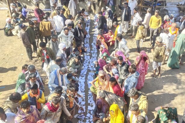 मध्य प्रदेश के राजगढ़ जिले में एक सहकारी विपणन समिति कार्यालय के दरवाजे पर किसान अपने आधार कार्ड और जमीन के दस्तावेज़ धागे से बांधकर यूरिया के लिए इंतज़ार कर रहे हैं।