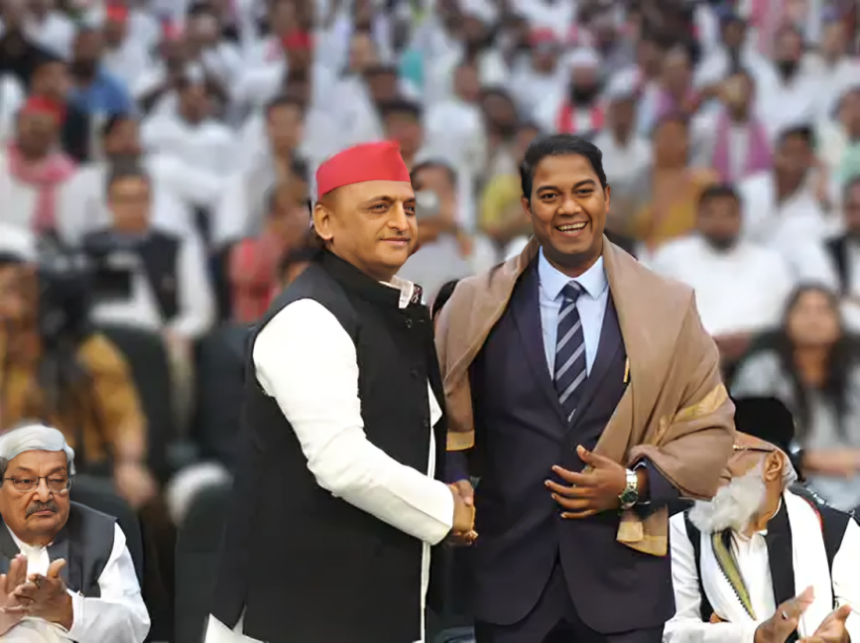 अखिलेश यादव और राजरतन अंबेडकर एक साथ हाथ उठाकर एकजुटता दिखाते हुए, बैकग्राउंड में 'समाजवादी पार्टी' और 'बाबा साहेब' के पोस्टर।