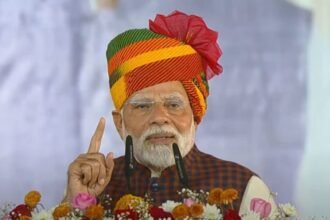 प्रधानमंत्री नरेंद्र मोदी गुजरात के साणंद में आयोजित कार्यक्रम के दौरान मंच से संबोधित करते हुए। पीएम मोदी ने 'सुन रहे हो न, विनोद' डायलॉग का जिक्र किया, जिसके बाद कार्यक्रम स्थल तालियों और ठहाकों से गूंज उठा
