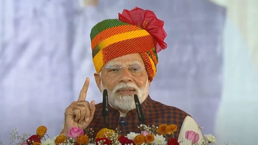 प्रधानमंत्री नरेंद्र मोदी गुजरात के साणंद में आयोजित कार्यक्रम के दौरान मंच से संबोधित करते हुए। पीएम मोदी ने 'सुन रहे हो न, विनोद' डायलॉग का जिक्र किया, जिसके बाद कार्यक्रम स्थल तालियों और ठहाकों से गूंज उठा